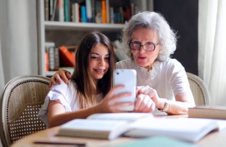 Ältere und jüngere Menschen nutzen gemeinsam ein mobiles Endgerät